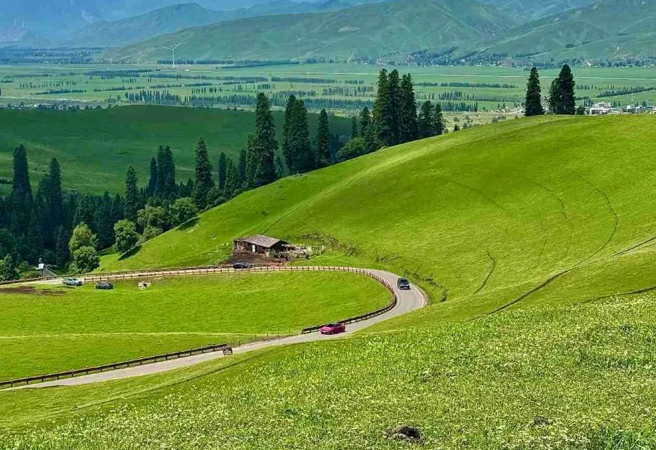 Nalati Grassland winding road across bright green summer hills, Xinjiang