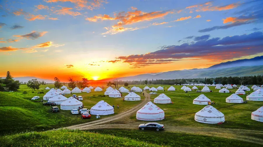 Nalati Grassland yurt camp at sunset under glowing clouds, Xinjiang