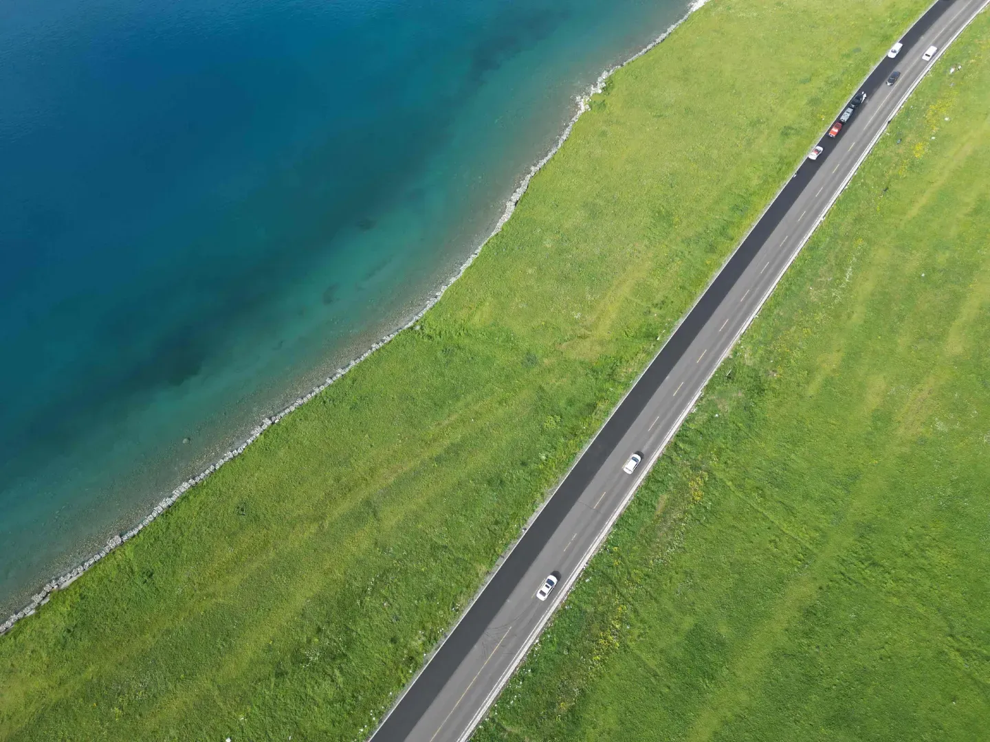 Sayram Lake aerial lakeside road along green summer meadow, Xinjiang