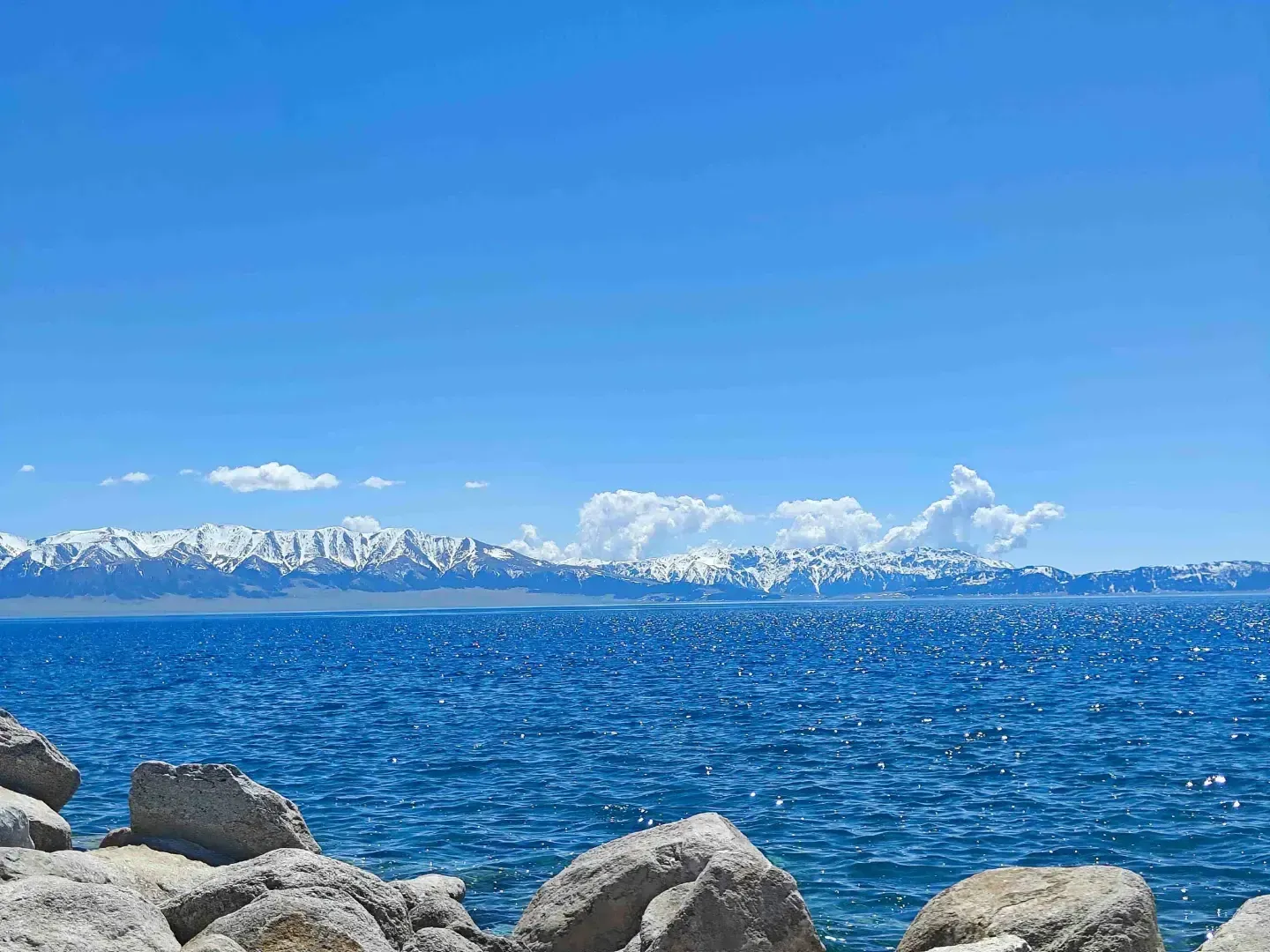 Sayram Lake rippling blue water below snowy peaks in summer, Xinjiang